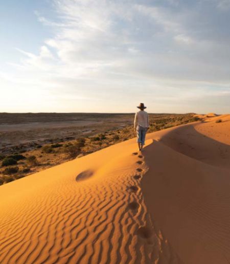 Person walking on top of sand dune or red sand