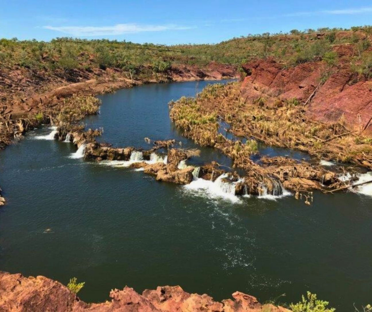 Looking down on river bend with riverbanks stripped of vegetation