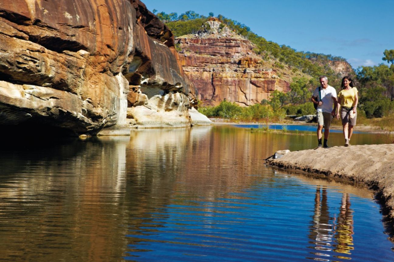 A man and a woman walk along narrow creek in the floor of the gorge. 