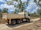 Photo of a dry, fairly flat dirt road with white truck on it