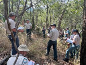Photo of rangers grouped together with notebooks in a national park undertaking planned burn training and familiarisation.