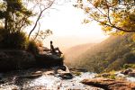 Person sitting on rock looking over waterfall