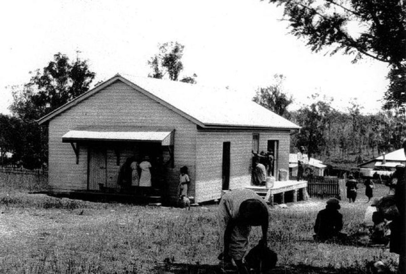 Image of Building with people standing on the verandah, and under awning
