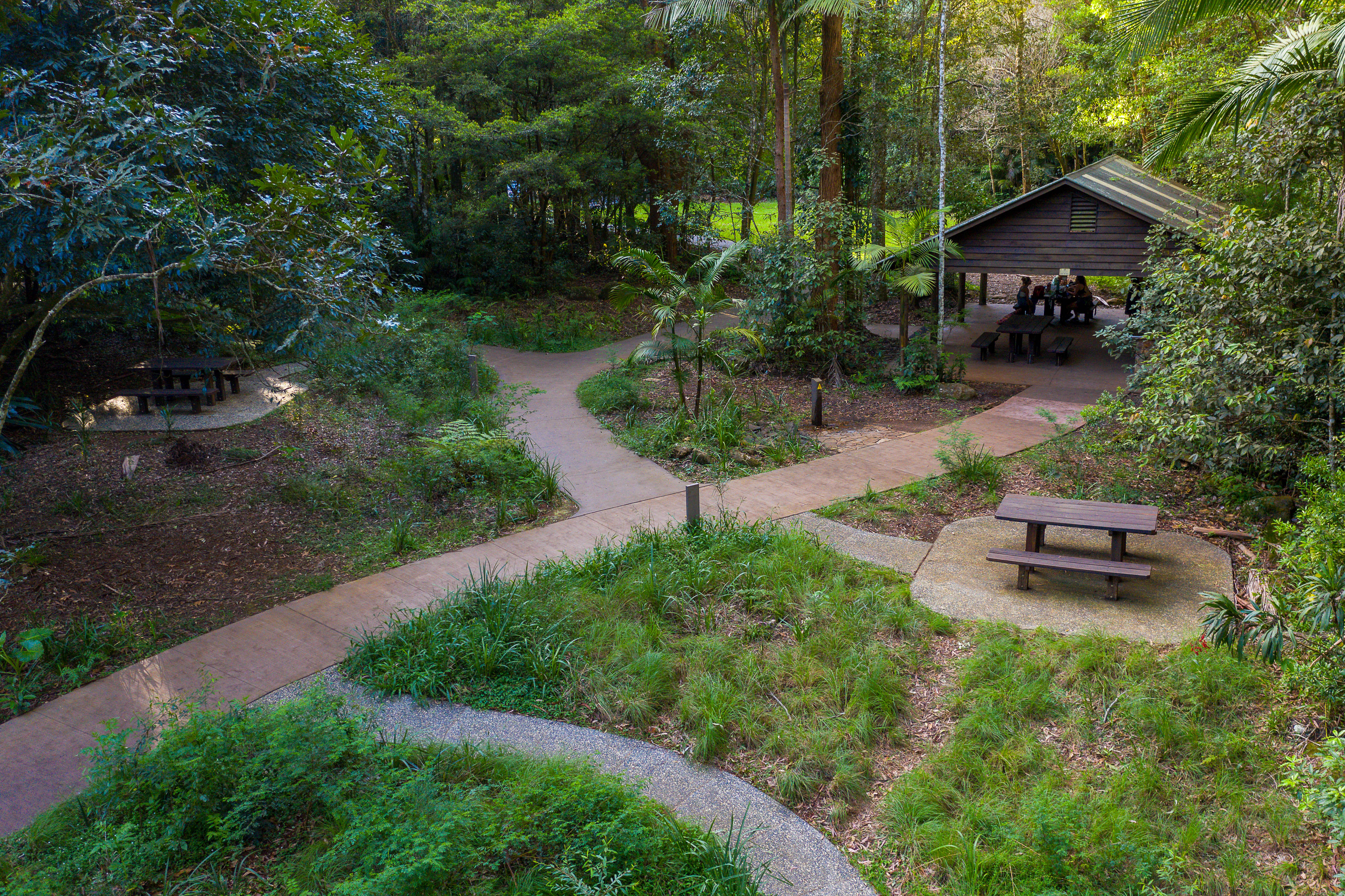 Sealed tracks lead to picnic tables in both open spaces and one under a roofed structure.