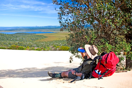 Photo of a walker sitting down in the shade on the sand.