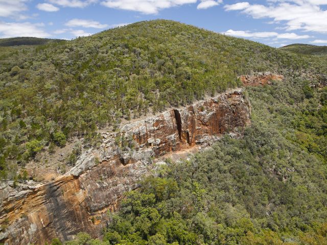 From Red Rock Gorge lookout, gaze across a dynamic deep gorge with high cliffs stained by red lichen.