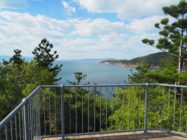 Photo from the lookout atop the WWII Searchlight Tower, with the lookout rails in the foreground and trees framing the beautiful ocean and coastline outlook.