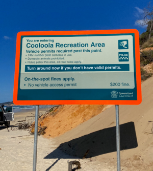 Photo of a beach, with an inset photo of the Middle Rocks cliffs and the warning signs.