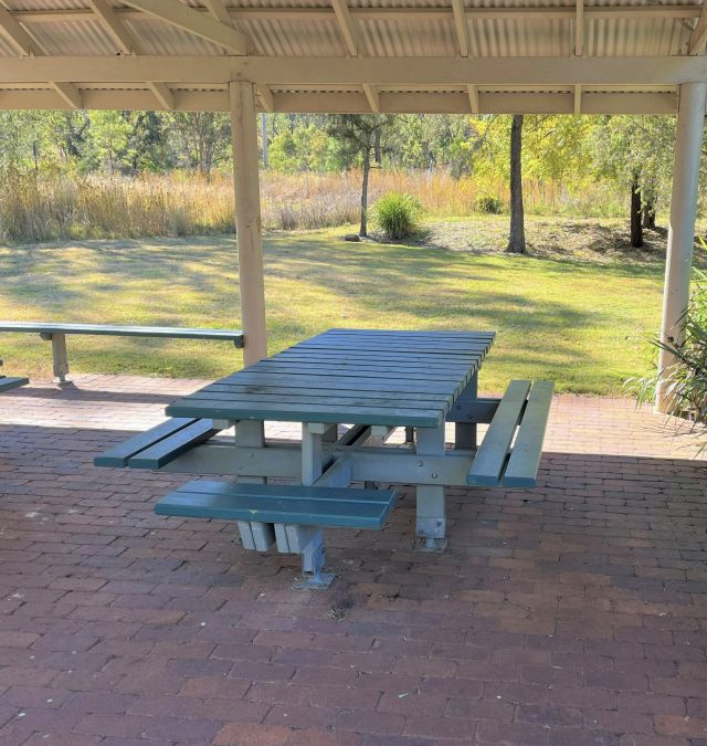 Sheltered picnic tables at Casuarina day-use area are set on either gravel or pavers with fixed chairs on all four sides.