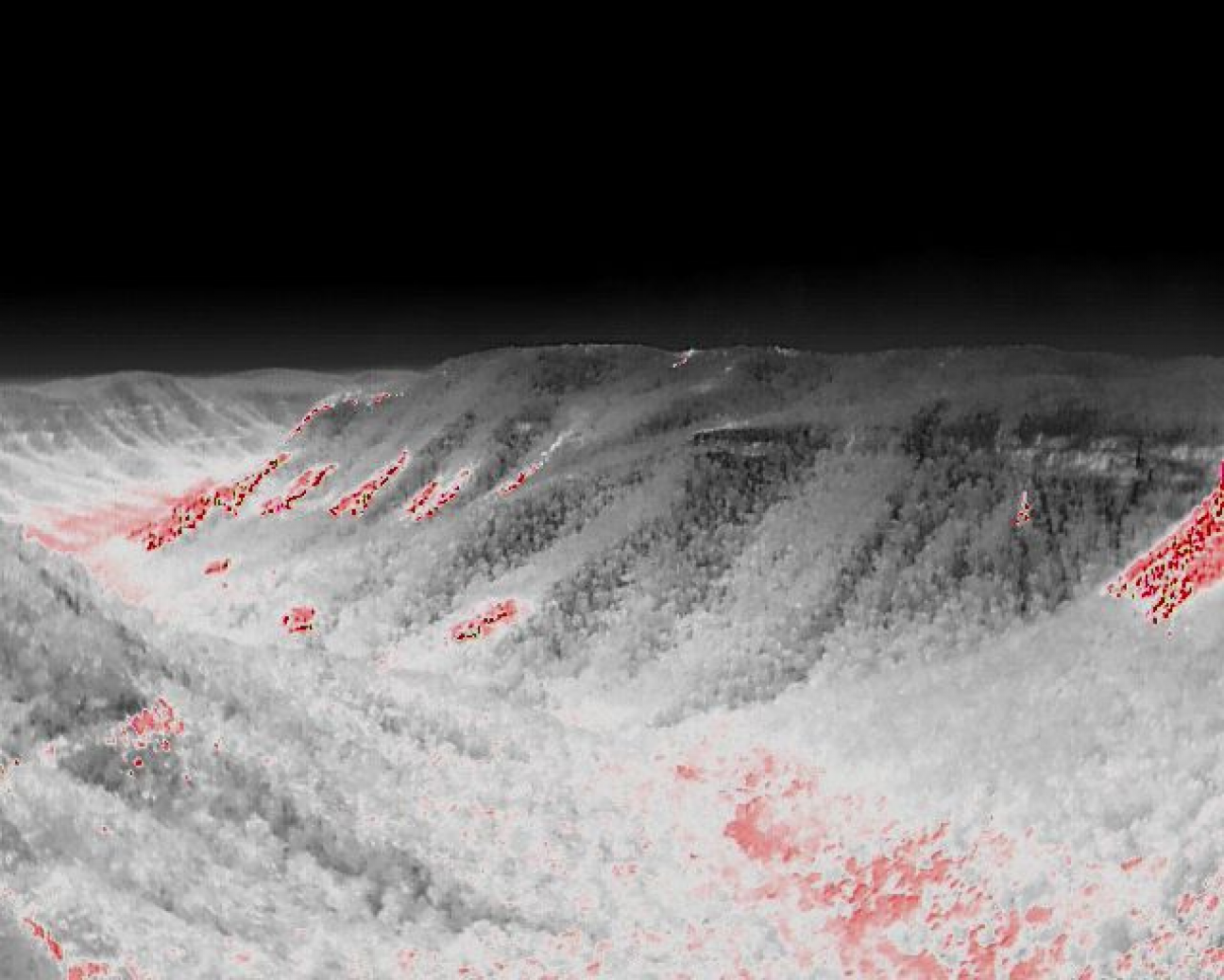Thermal aerial image of forested hills showing multiple bushfire hotspots highlighted in red, indicating areas of higher heat across the landscape.