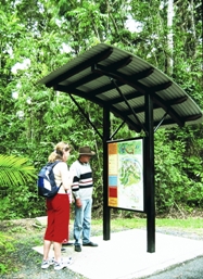 Visitors standing reading sheltered walking track signs.