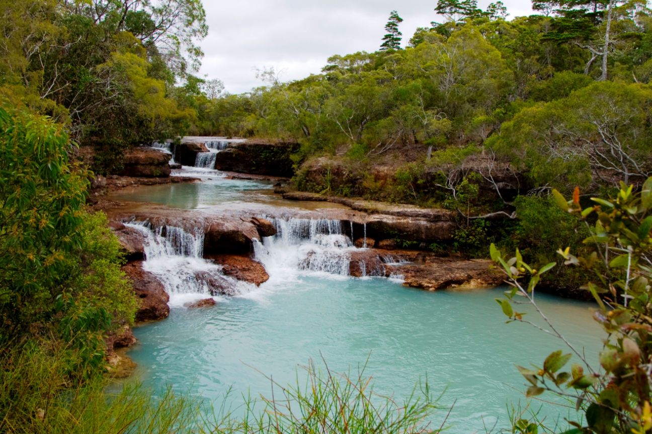 Small waterfalls cascading over rocky banks into opaque water with light blue tinge