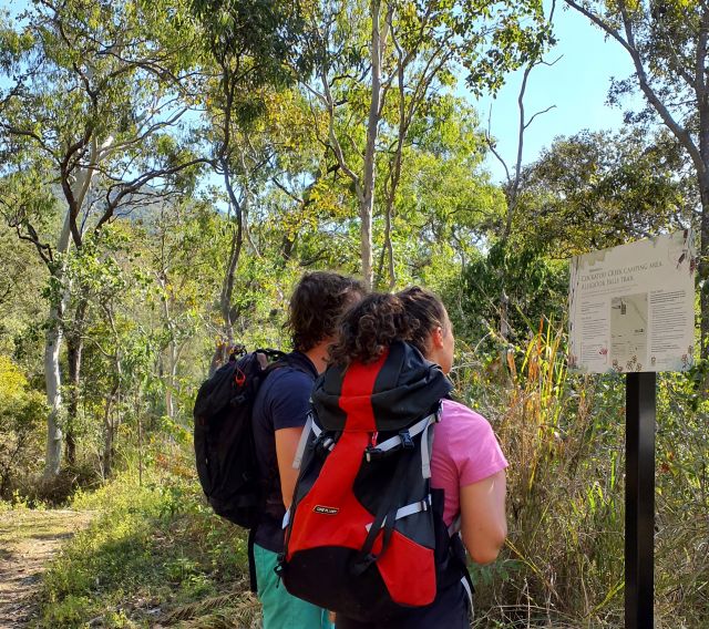 Two people wearing backpacks looking at signage