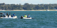 Two small boats on water with staff rescuing stranded whale