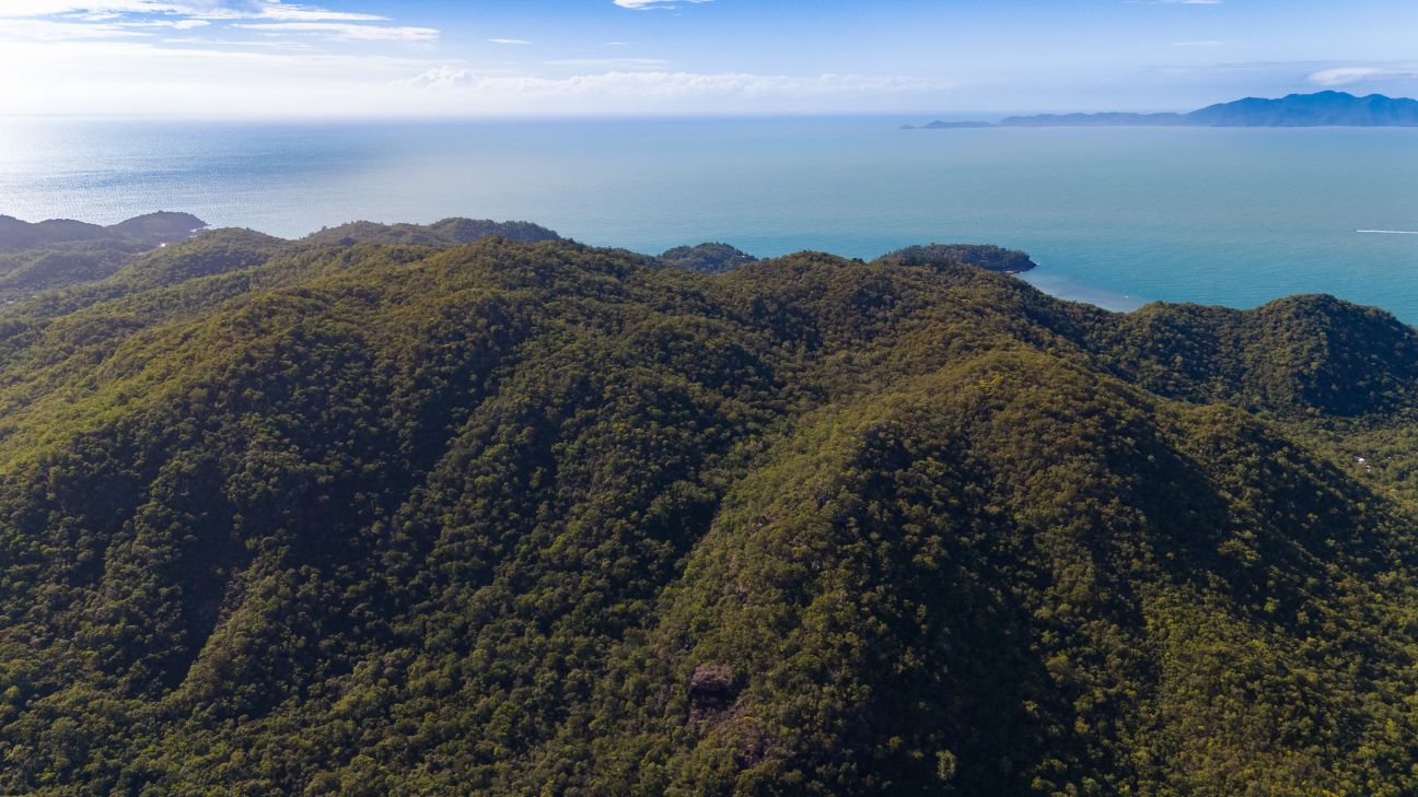Aerial view over Magnetic Island. Green forested mountainous Island. Blue ocean.