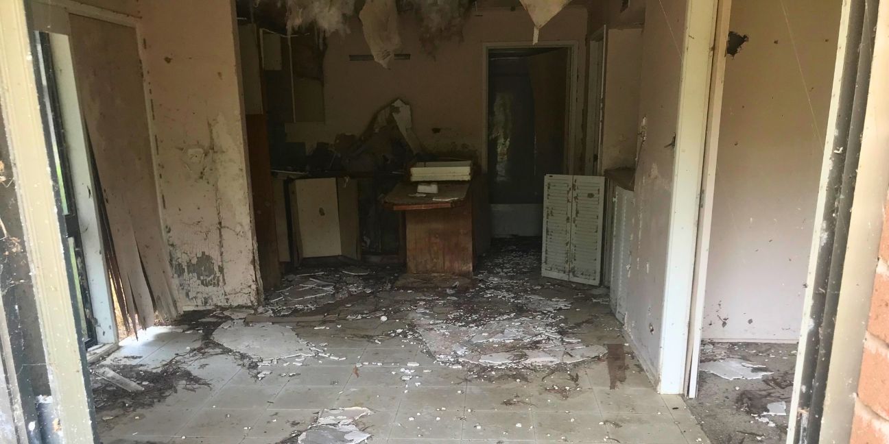 Looking inside one of the abandon villas. The roof is falling down, the walls are coming apart, there’s broken cupboards and broken tiles on the floor.