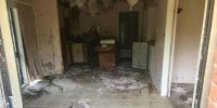 Looking inside one of the abandon villas. The roof is falling down, the walls are coming apart, there’s broken cupboards and broken tiles on the floor.