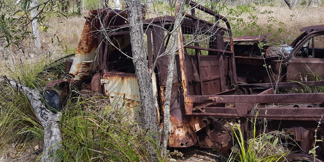 Rusty chaises of an abandoned 4WD vehicle and car.