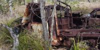 Rusty chaises of an abandoned 4WD vehicle and car.